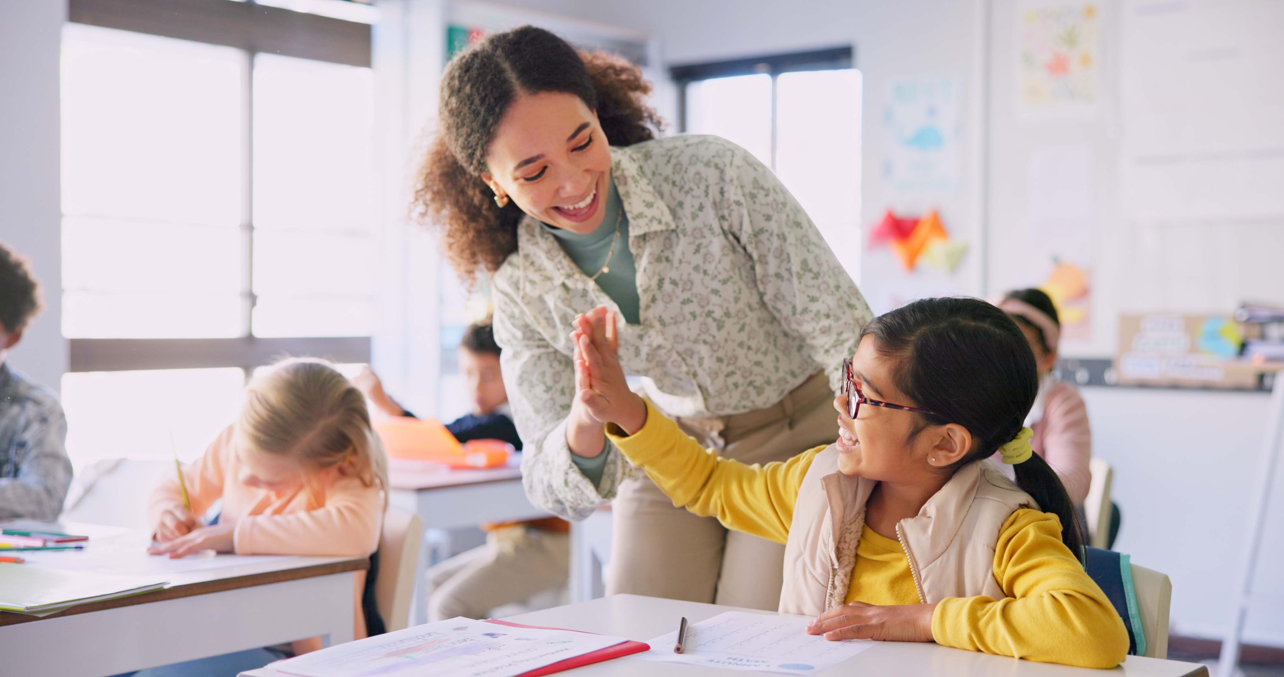 Teacher giving a student a high five in a classroom